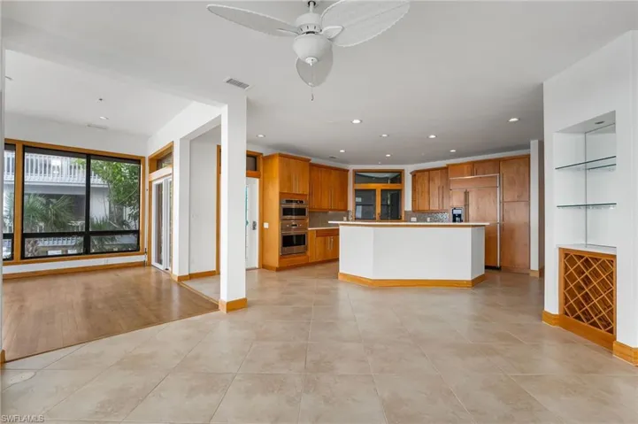 Kitchen featuring open floor plan, brown cabinetry, paneled refrigerator, light tile patterned flooring, and recessed lighting
