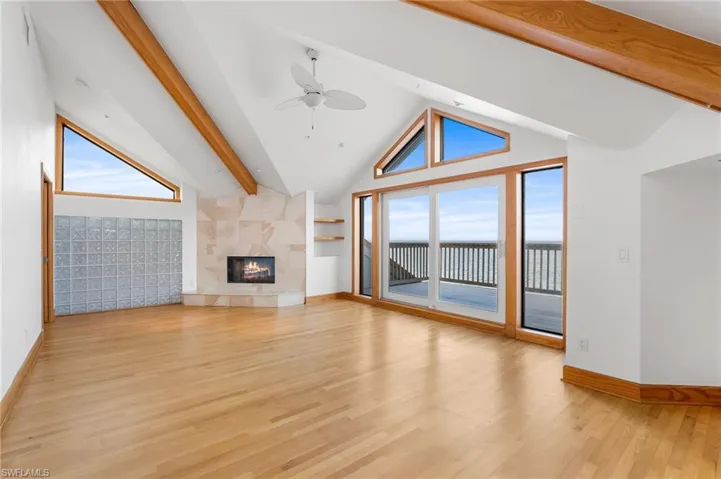 Master bedroom featuring wood beams, ceiling fan, light wood finished floors, a premium fireplace, and a water view