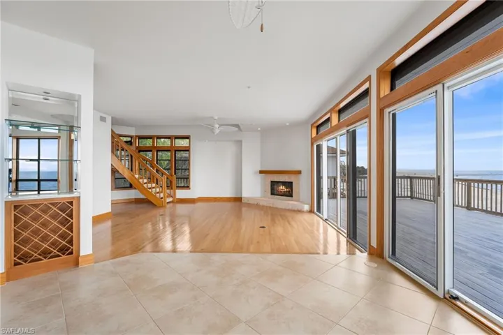 Unfurnished living room featuring tile patterned flooring, a tiled fireplace, a water view, stairs, and ceiling fan