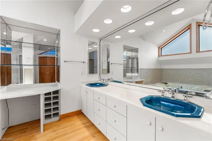Full bathroom with double vanity, wood finished floors, recessed lighting, and a bath
