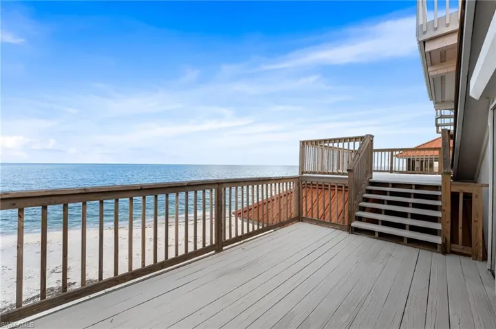 Wooden terrace with view of water and beach and stairs