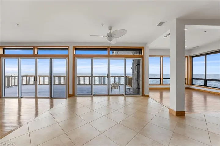 Empty room featuring light tile patterned flooring, a water view, and ceiling fan
