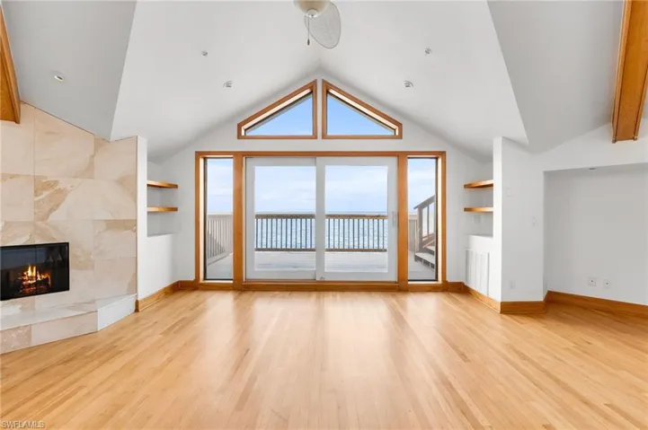 Unfurnished living room with vaulted ceiling, wood finished floors, and a tiled fireplace