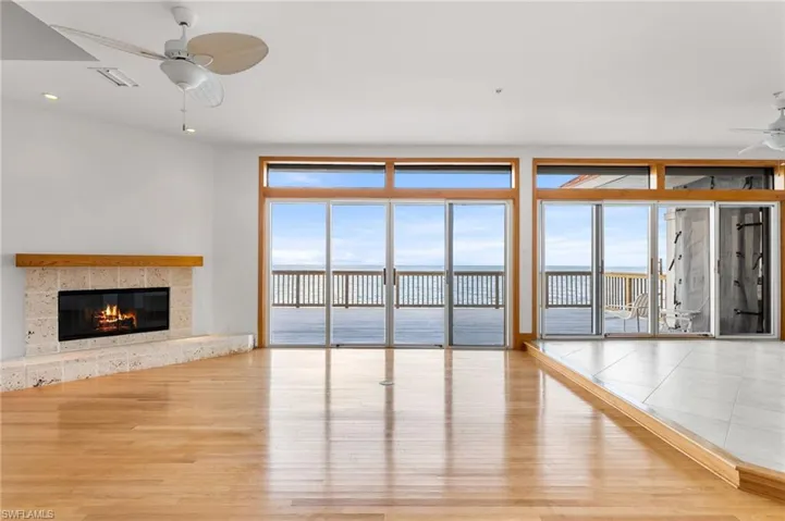 Unfurnished living room with ceiling fan, a water view, wood finished floors, a high end fireplace, and recessed lighting