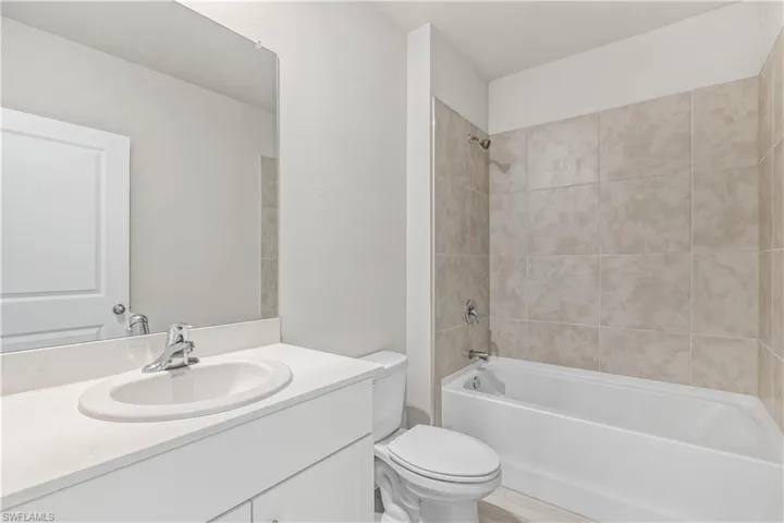 Full bathroom with vanity, tiled shower / bath combo, and toilet