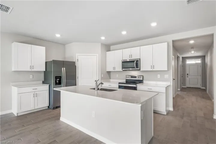 Kitchen with a center island with sink, white cabinetry, light hardwood / wood-style flooring, sink, and stainless steel appliances