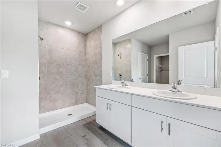 Bathroom featuring vanity, wood-type flooring, and tiled shower