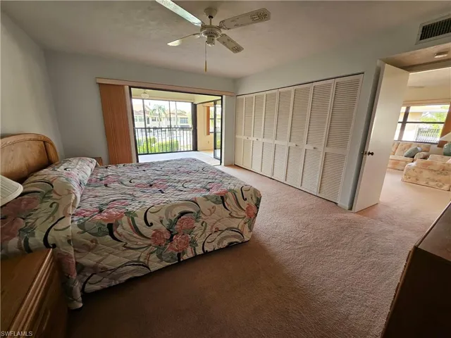Carpeted bedroom with ceiling fan and a large closet