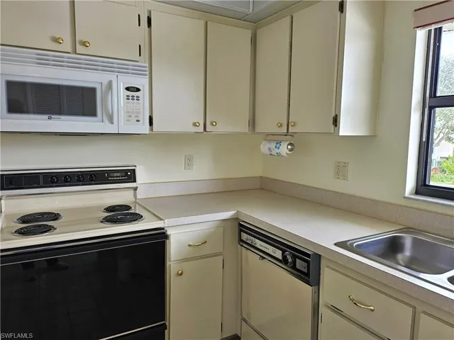 Kitchen with sink, electric range, dishwasher, and cream cabinetry