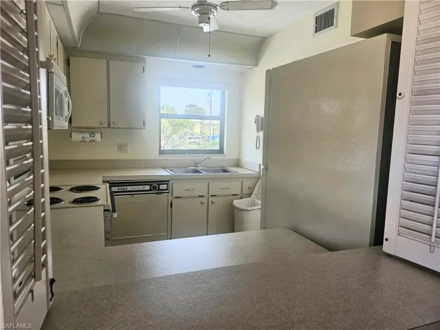 Kitchen featuring ceiling fan, dishwashing machine, sink, and stovetop