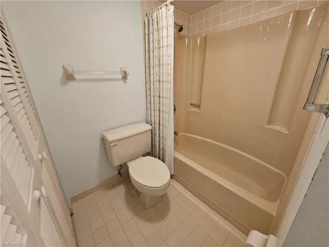 Bathroom with toilet, tile patterned flooring, and shower / tub combo with curtain