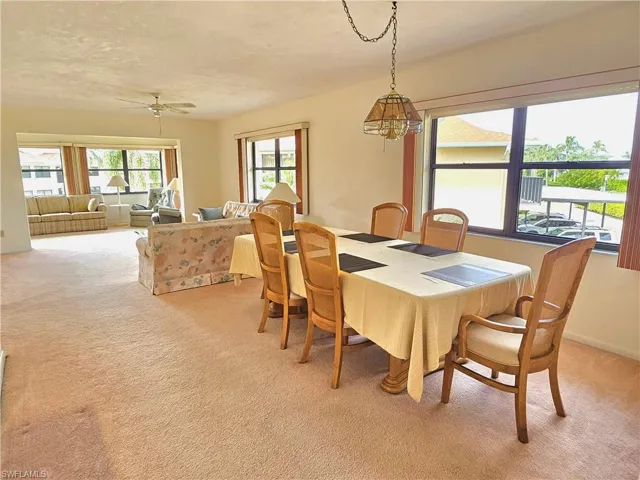 Carpeted dining space featuring ceiling fan with notable chandelier