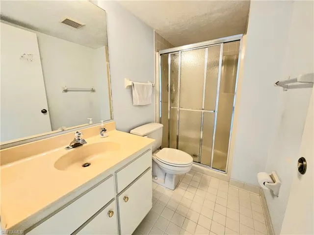 2ND Bathroom with toilet, vanity, tile patterned floors, a textured ceiling, and an enclosed shower