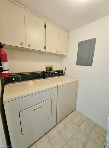 Laundry room featuring cabinets, electric panel, and washing machine and dryer