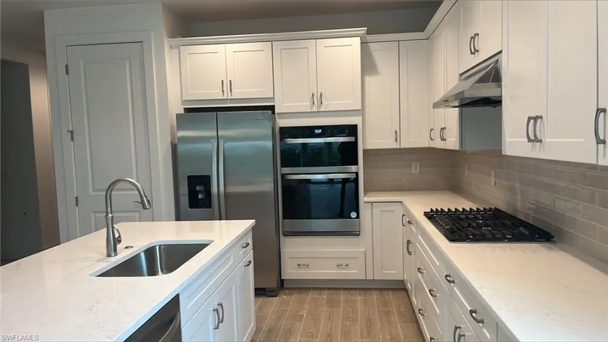 Kitchen layout with Whirlpool kitchen appliances-- refrigerator, dishwasher, gas cooktop, wall oven, and wall microwave