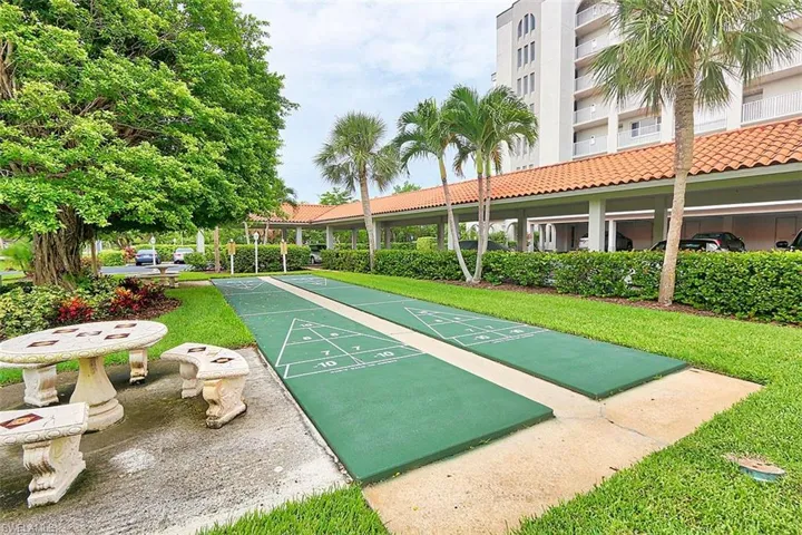 View of home's community featuring shuffleboard and a lawn
