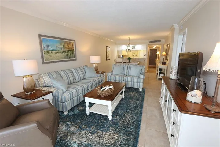 Living room with ornamental molding, light tile patterned floors, and a chandelier