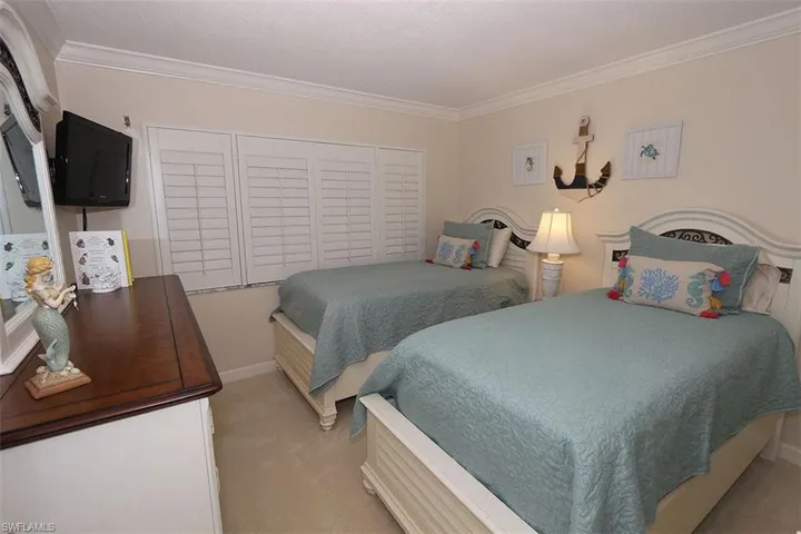 Bedroom with crown molding and light colored carpet