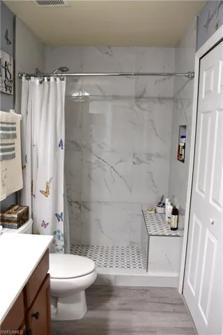 Bathroom featuring vanity and a marble finish shower