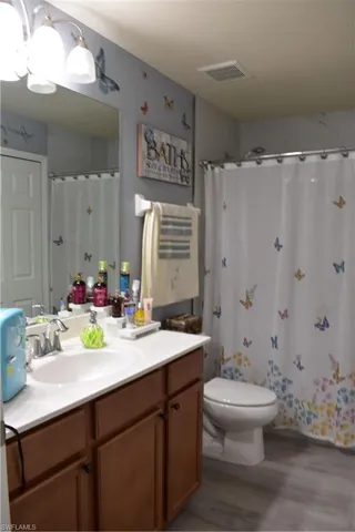 Full bath with vanity, a shower with shower curtain, and light wood-type flooring