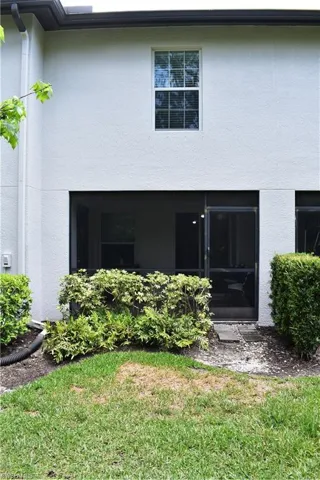 Back of property featuring stucco siding, a yard, and a sunroom