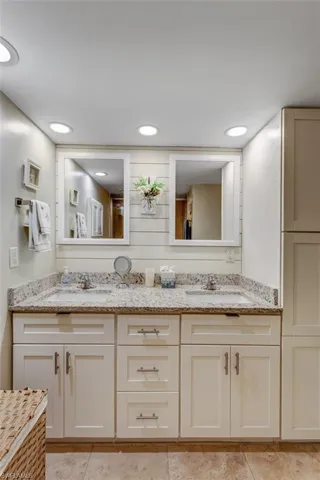Bathroom with double vanity, recessed lighting, and light tile patterned floors