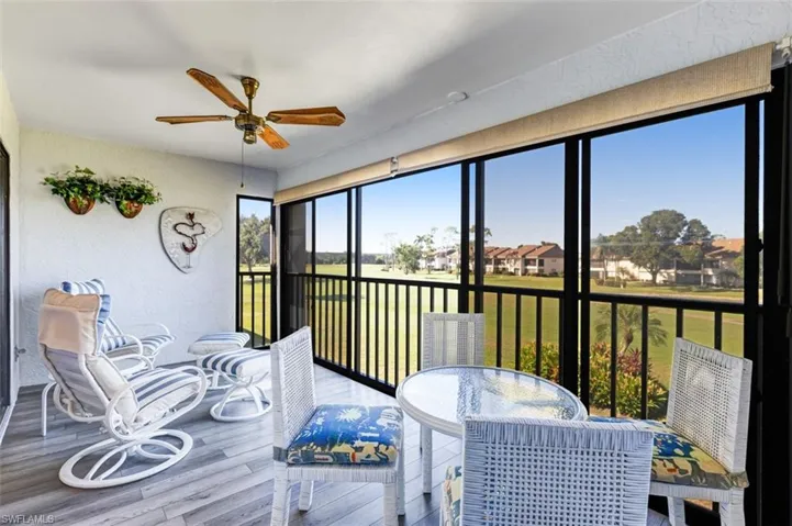 Lanai featuring a textured wall, wood finished floors, ceiling fan, outdoor dining area, and a water view