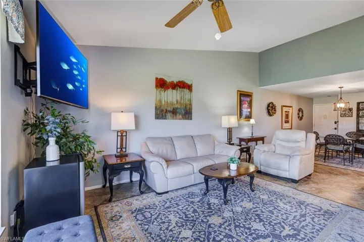 Living area featuring vaulted ceiling, ceiling fan, and a chandelier