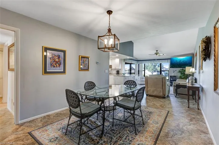 Dining area with a chandelier, light stone finish floors, and a ceiling fan