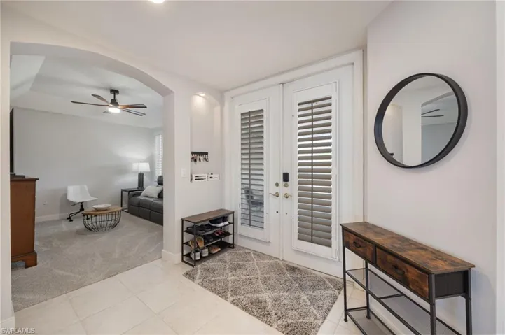 Foyer featuring arched walkways, a ceiling fan, light tile patterned floors, and light colored carpet