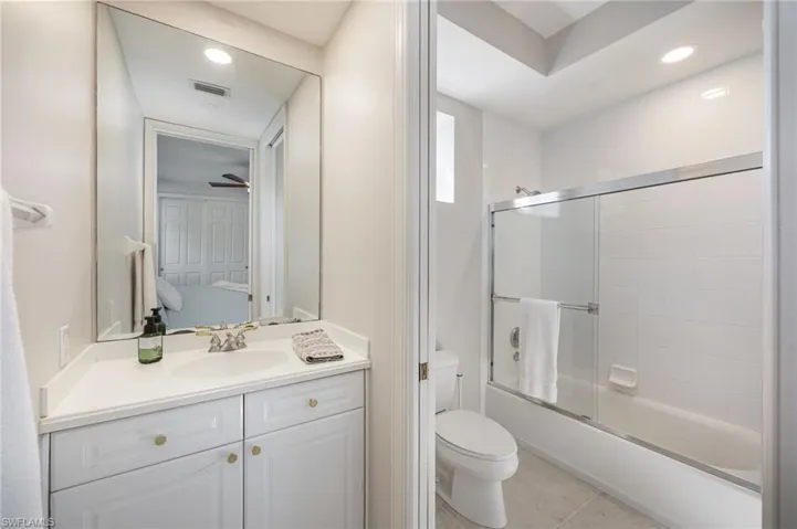 Bathroom with vanity, combined bath / shower with glass door, light tile patterned floors, and recessed lighting