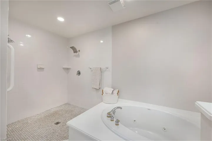 Bathroom with tiled shower, a jetted tub, and recessed lighting
