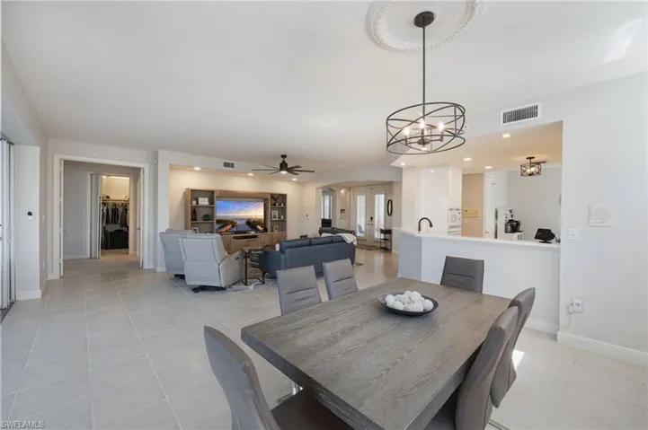 Dining space featuring light tile patterned flooring, arched walkways, hanging lights, and a ceiling fan