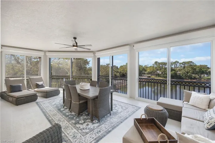 Sunroom / solarium with a textured ceiling, a water view, and tile patterned floors
