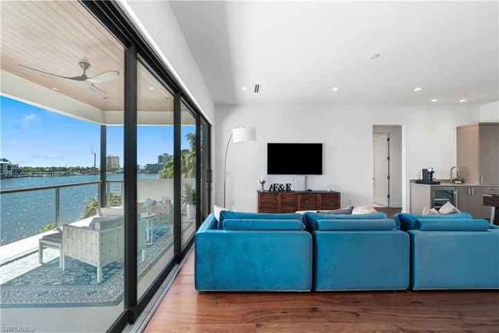 Living room with ceiling fan, a water view, hardwood / wood-style flooring, and a healthy amount of sunlight