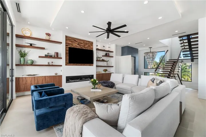 Tiled living room featuring built in shelves, a baseboard heating unit, and ceiling fan