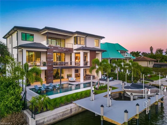 Back house at dusk featuring a balcony and a patio