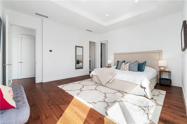 Bedroom with dark hardwood / wood-style flooring and a raised ceiling