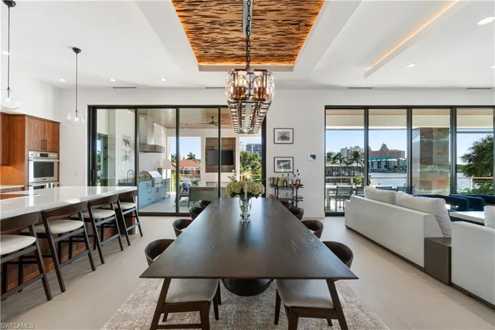 Dining room with light tile patterned floors, a chandelier, and a tray ceiling