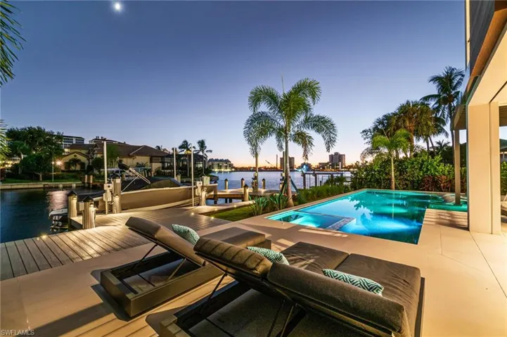 Pool at dusk with a water view and a boat dock