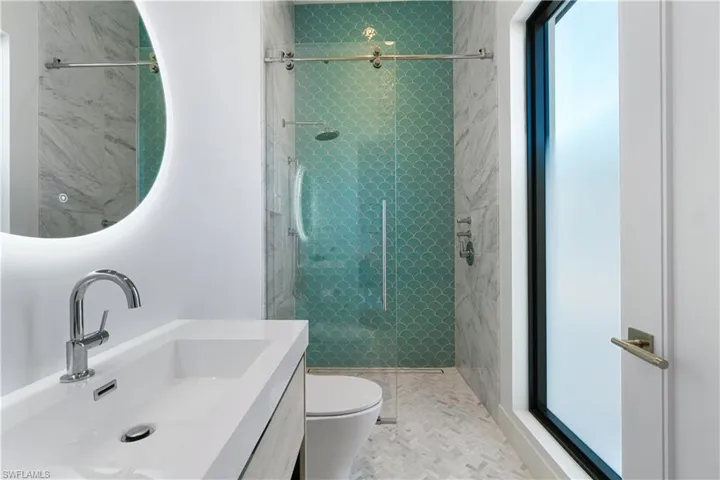 Bathroom with an enclosed shower, vanity, and toilet