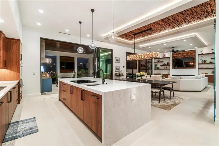 Kitchen featuring ceiling fan, an island with sink, sink, and pendant lighting