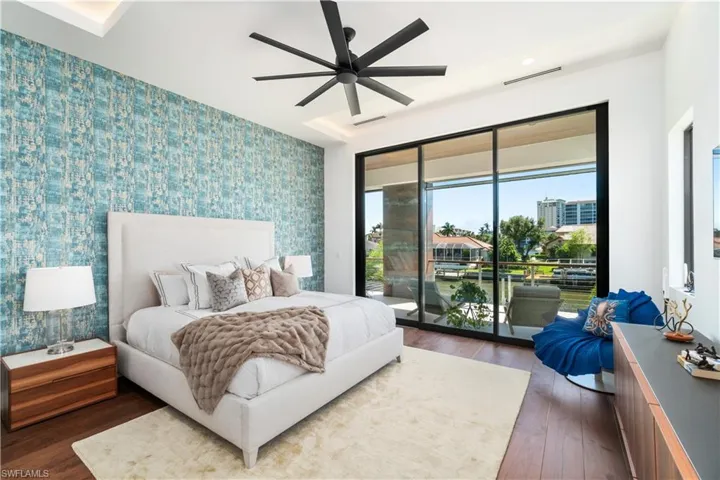 Bedroom featuring access to exterior, wood-type flooring, a tray ceiling, and ceiling fan