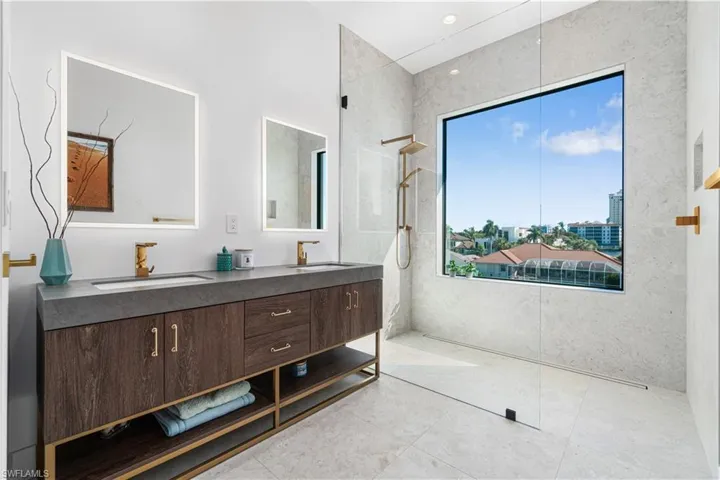 Bathroom featuring double sink vanity, a tile shower, and tile patterned flooring