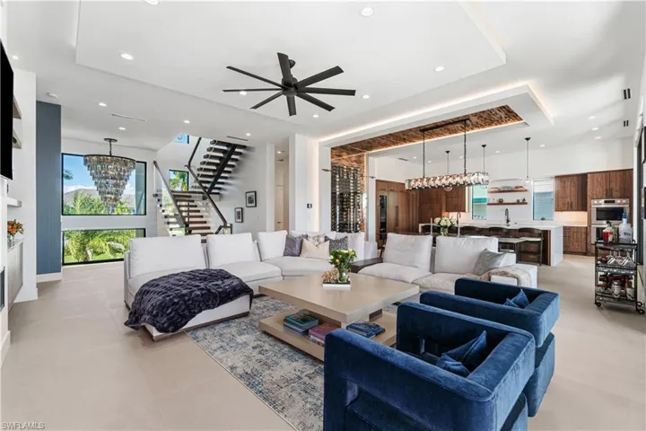 Tiled living room featuring ceiling fan with notable chandelier