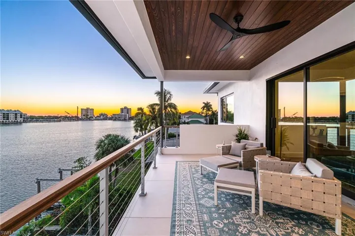Balcony at dusk featuring a water view and ceiling fan