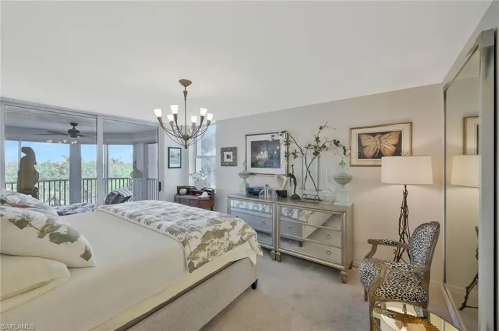Bedroom with access to outside, a chandelier, and light carpet