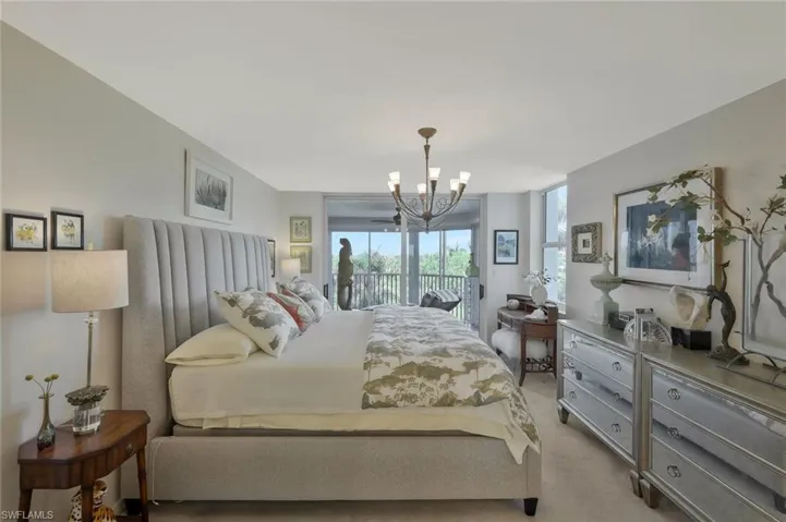 Bedroom featuring access to outside, light colored carpet, and a chandelier