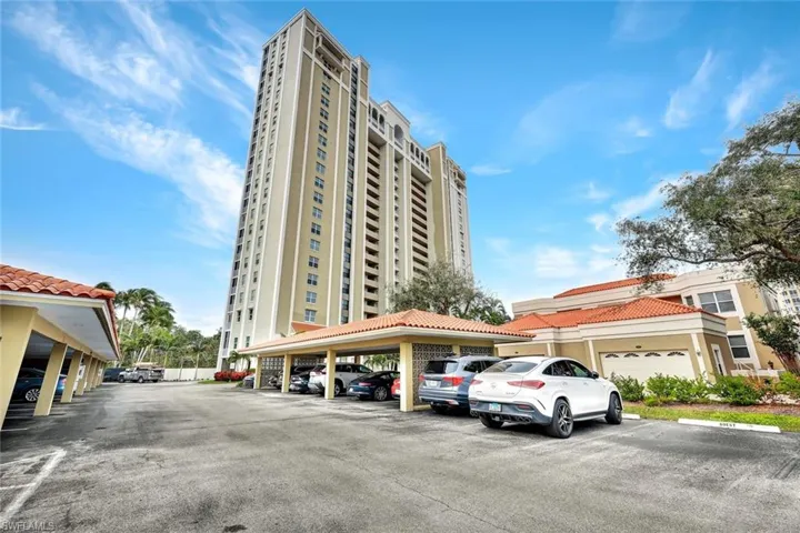 View of apartment building / complex featuring covered and uncovered parking