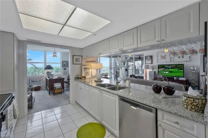 Kitchen with appliances with stainless steel finishes, open floor plan, light stone countertops, and plenty of natural light